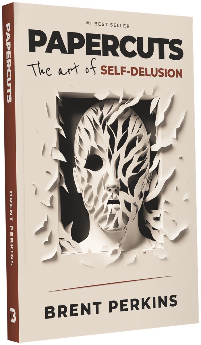 Papercuts: The Art of Self-Delusion, by Brent Perkins. The book seen at an angle, with its spine showing.